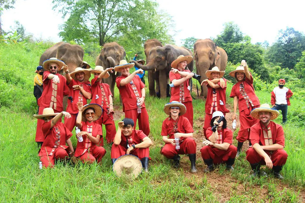 Amazing Full Day Program 19 a group of people in red outfits posing for a picture with elephants